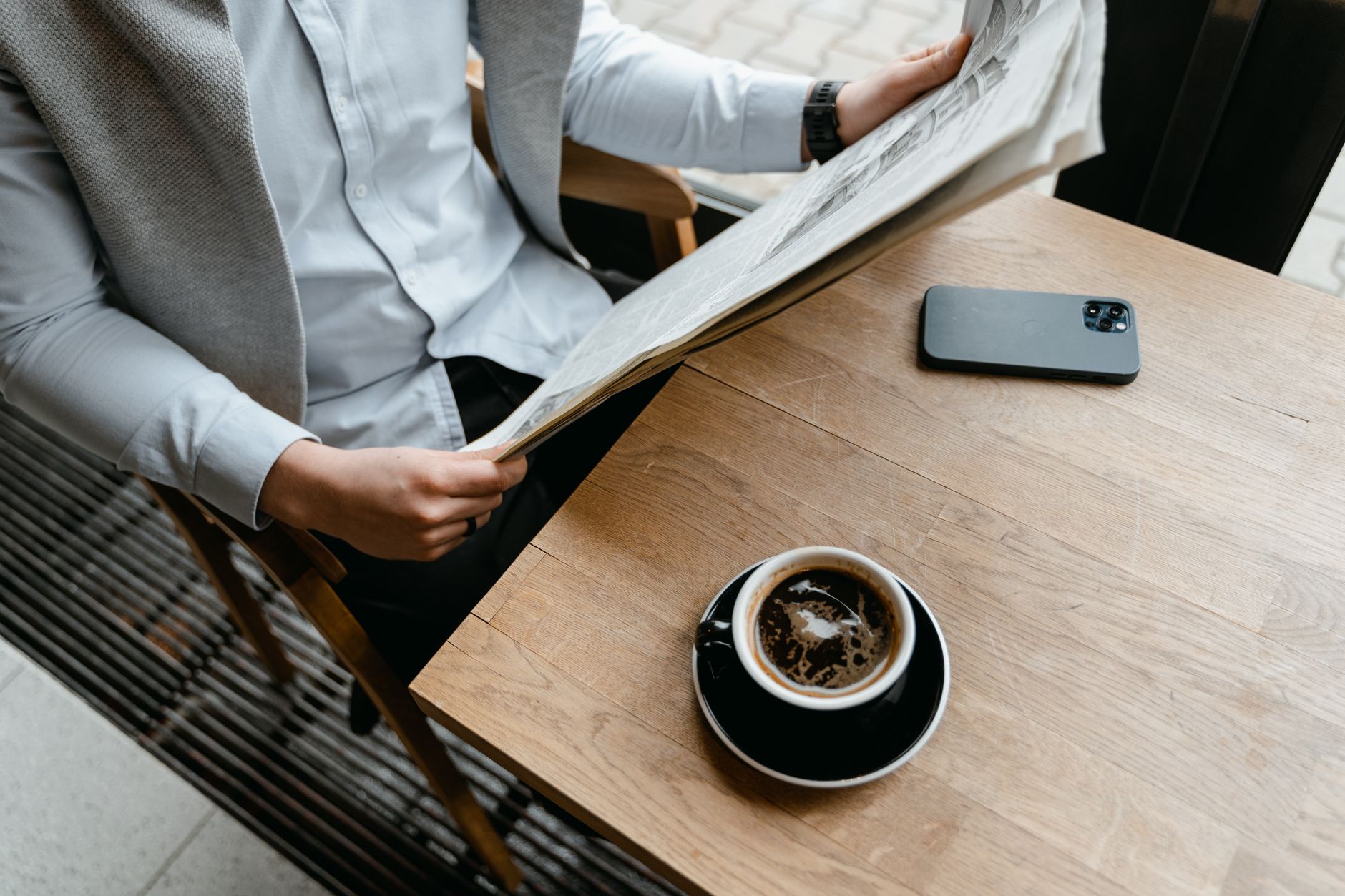 An adult male enjoying his coffee while reading a newspaper at a cafe with his smartphone nearby. — Ally Spin Casino: Analyse