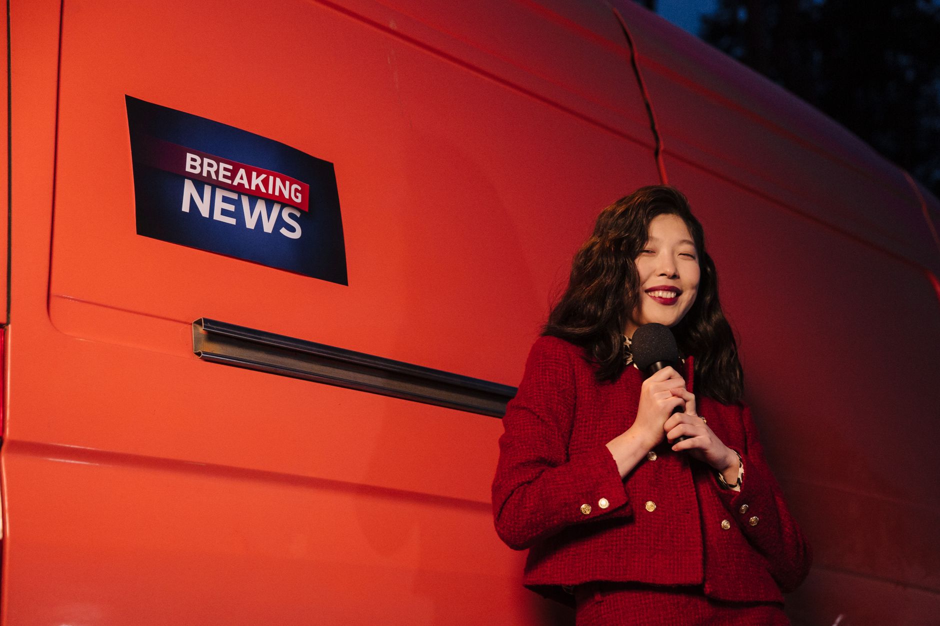Asian female reporter smiling with microphone besides a news van at night. — Comment Lucky 31 Casino conjugue innovation et t