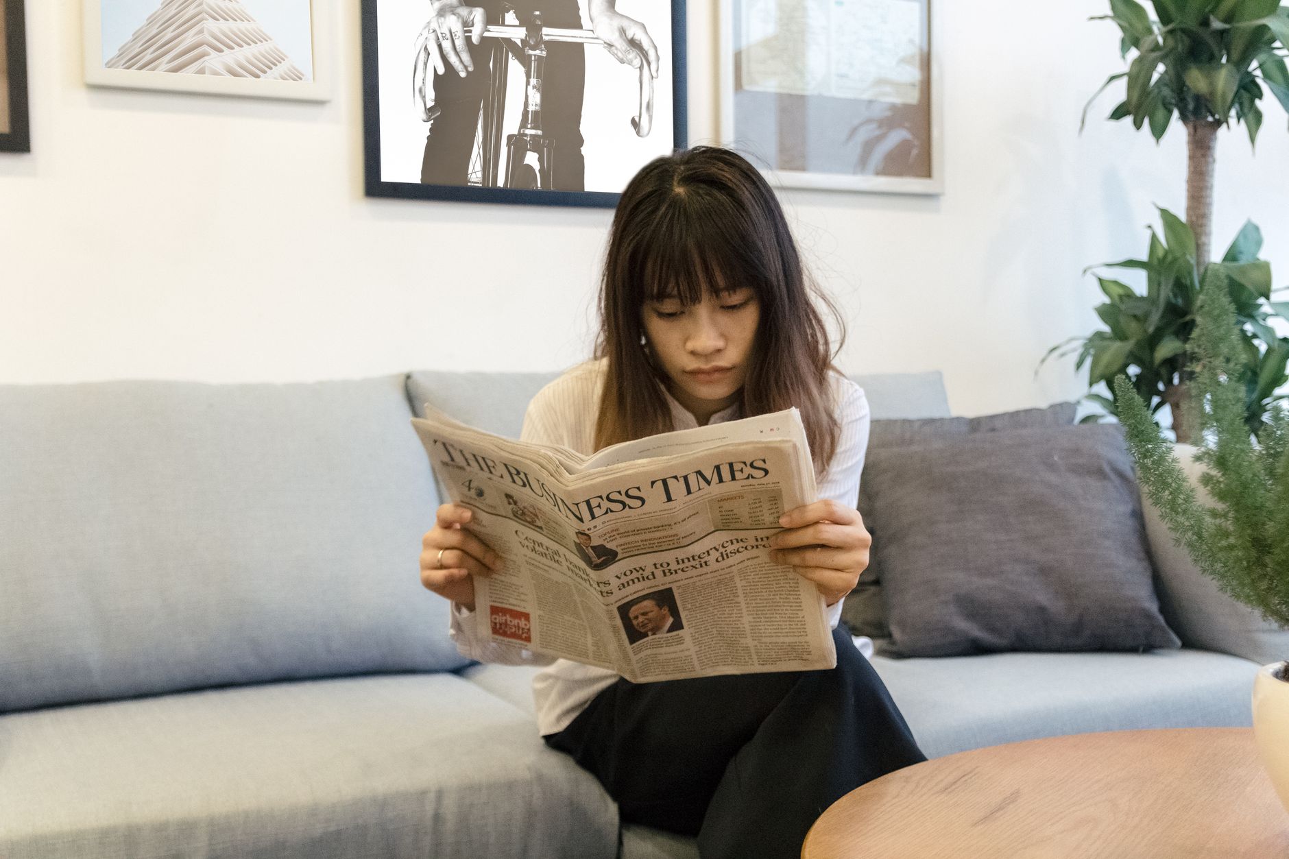 A young woman attentively reads a newspaper while sitting on a modern sofa indoors. — Comparez la fiabilité de Shiny Wilds Ca