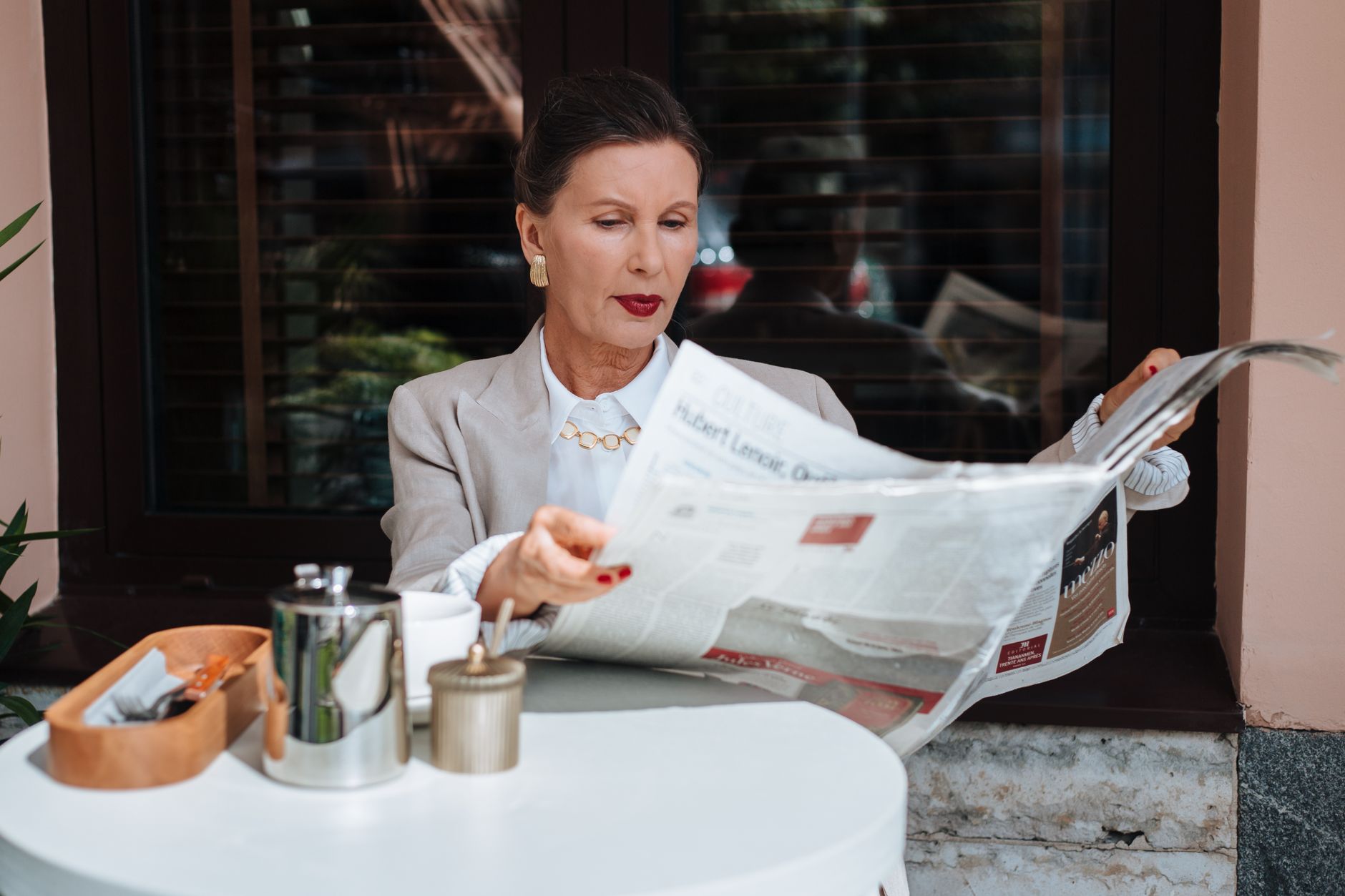 Sophisticated woman enjoying her morning newspaper at a cozy outdoor cafe. — Die mobile App von SpinCastle Casino: Einsteiger