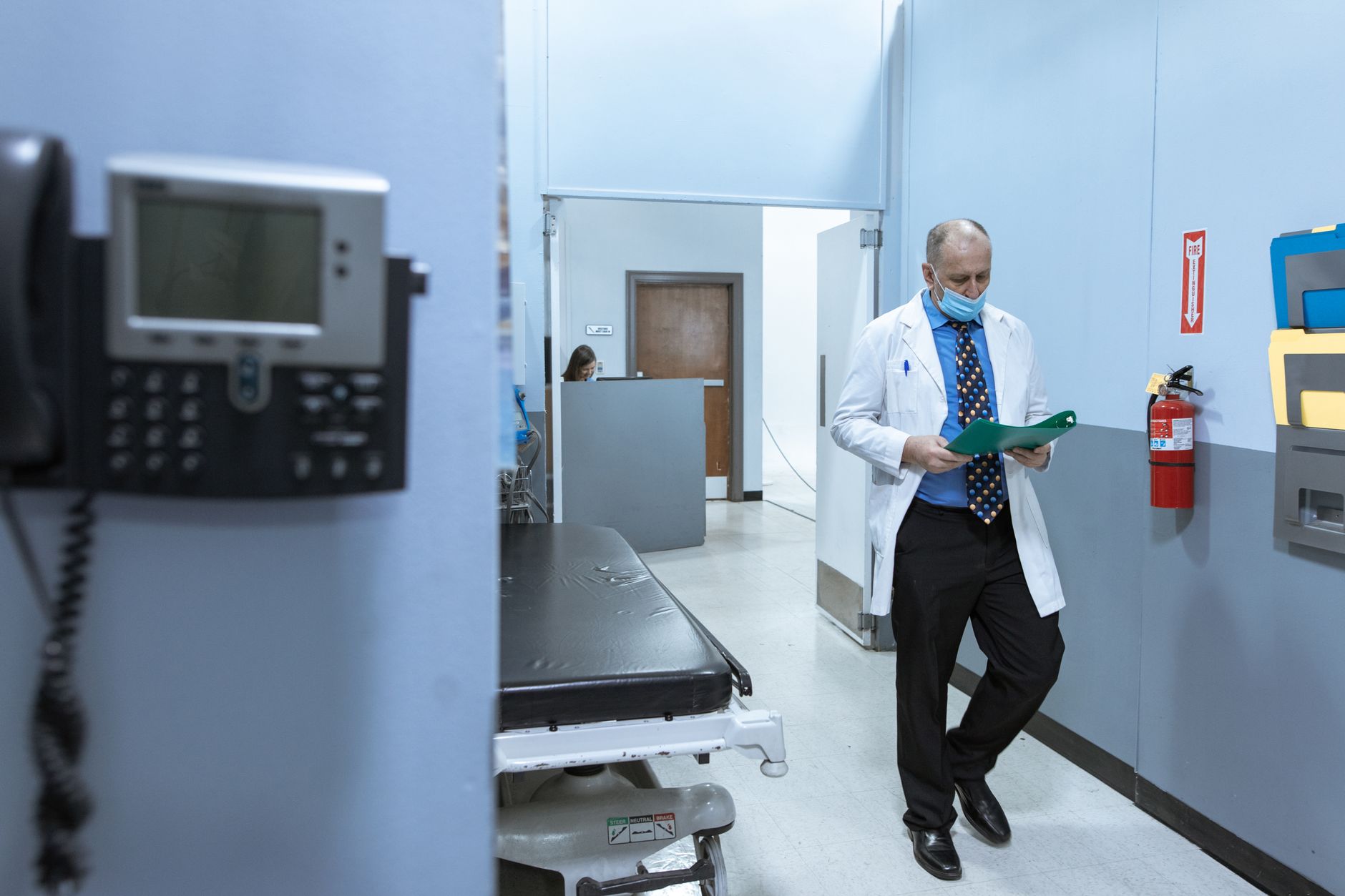 A doctor in a lab coat reads medical files in a hospital hallway, illustrating professional healthcare settings. — How Dermal