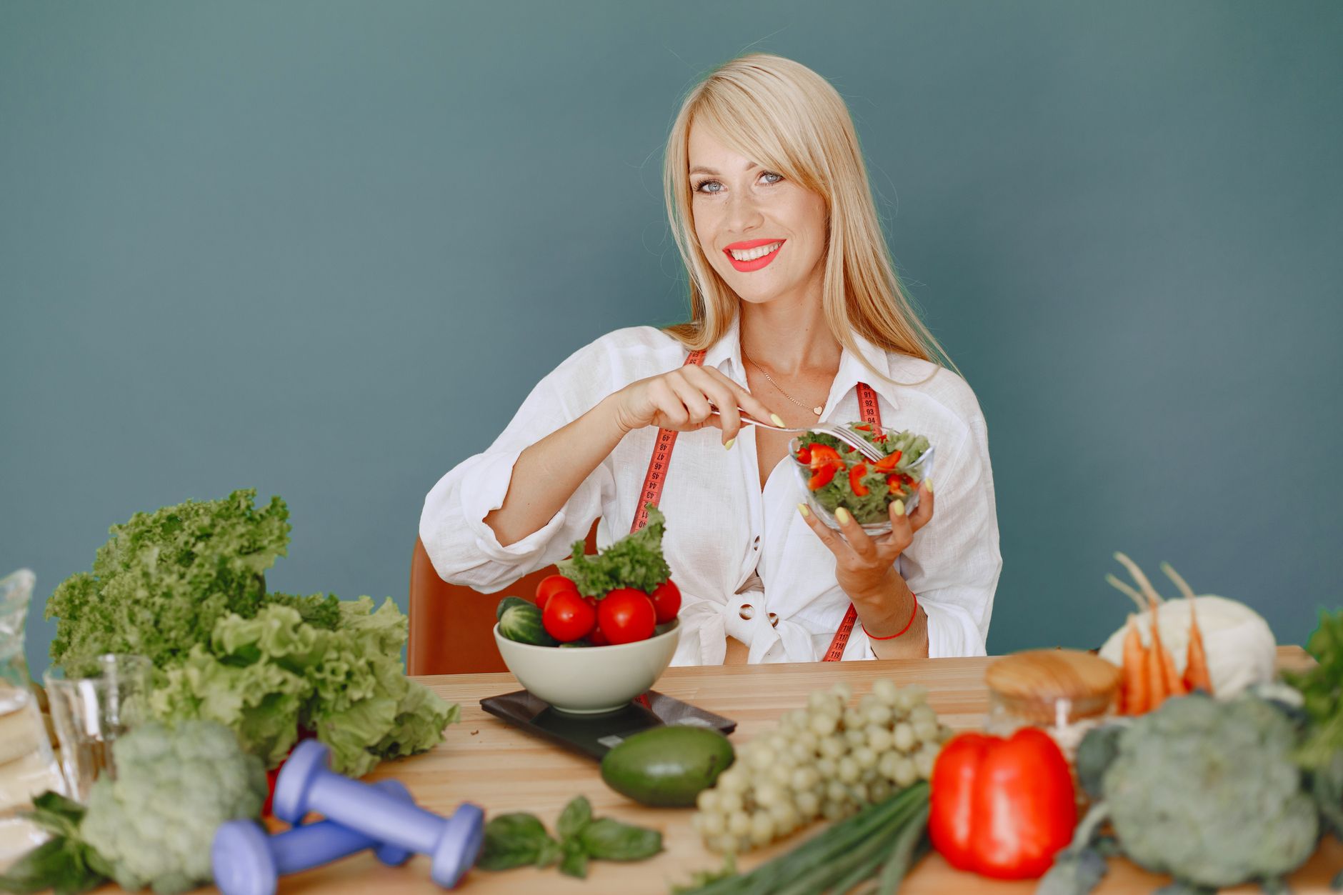 Blonde woman enjoying a fresh salad surrounded by vegetables, promoting healthy eating. — How Myers Cocktail IV infusion Usef