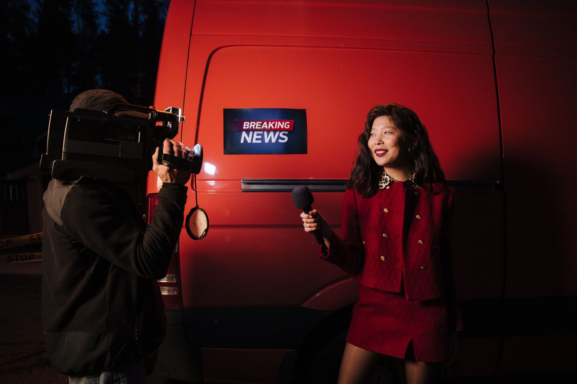 Dynamic news reporter holding microphone near red van during nighttime outdoor broadcast. — Kann Casoo Casino mit den großen