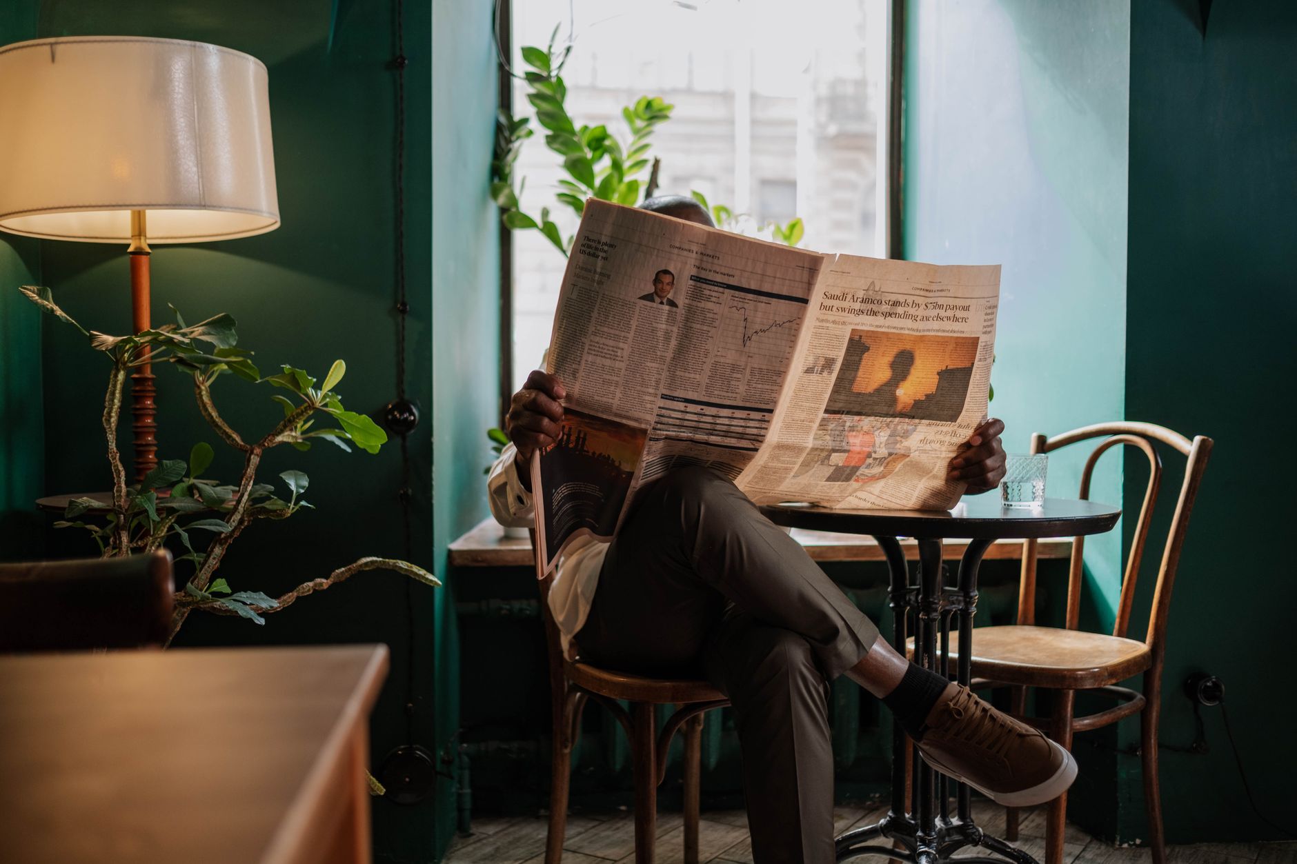 A man sits in a cozy café corner, enjoying a newspaper and relaxed ambiance. — King Chance Casino un monde de jeux sécurisé p