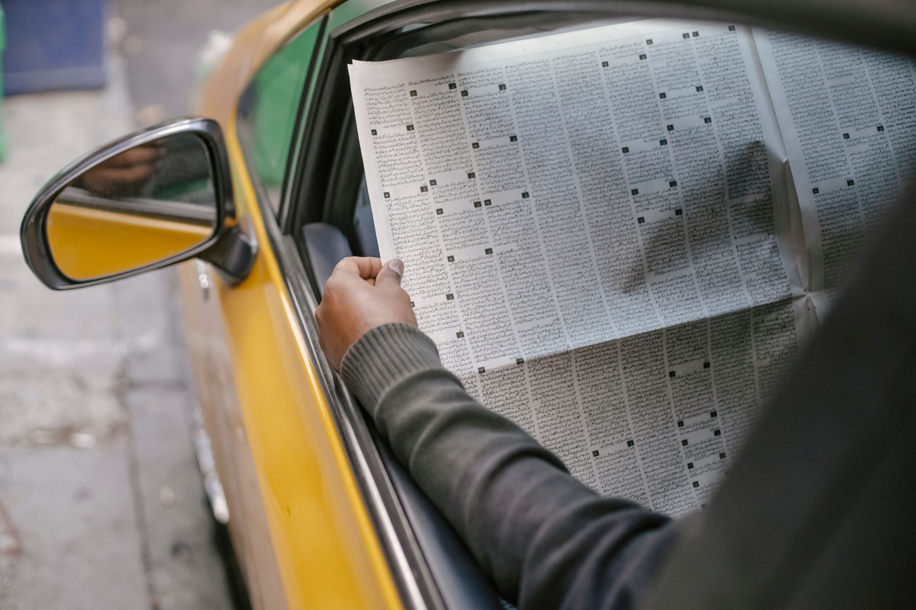 Crop unrecognizable person reading daily newspaper while sitting in car with opened window — Les avis authentiques sur Manga