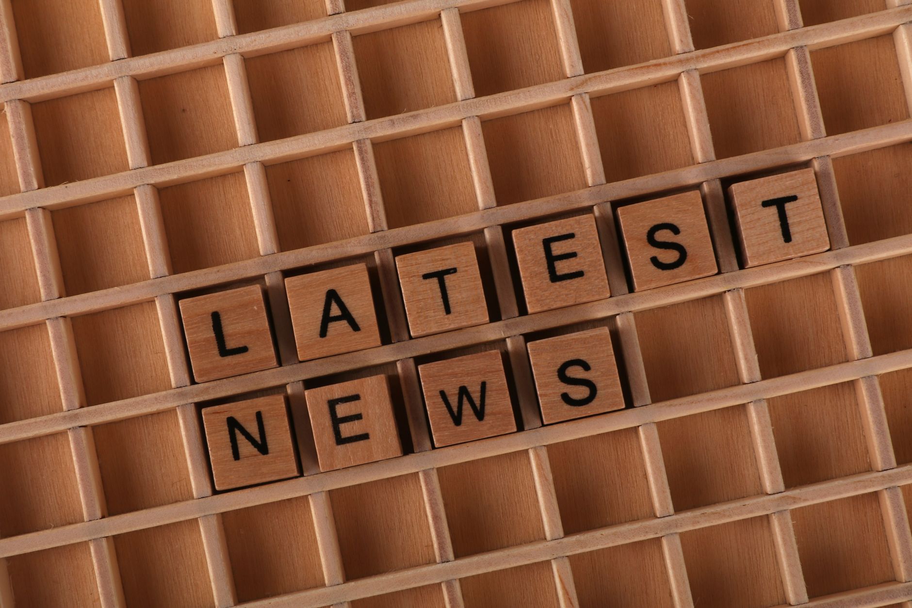 Wooden letter blocks spelling 'Latest News' on a grid surface. Ideal for media concepts. — Les nouveautés du calendrier bonus