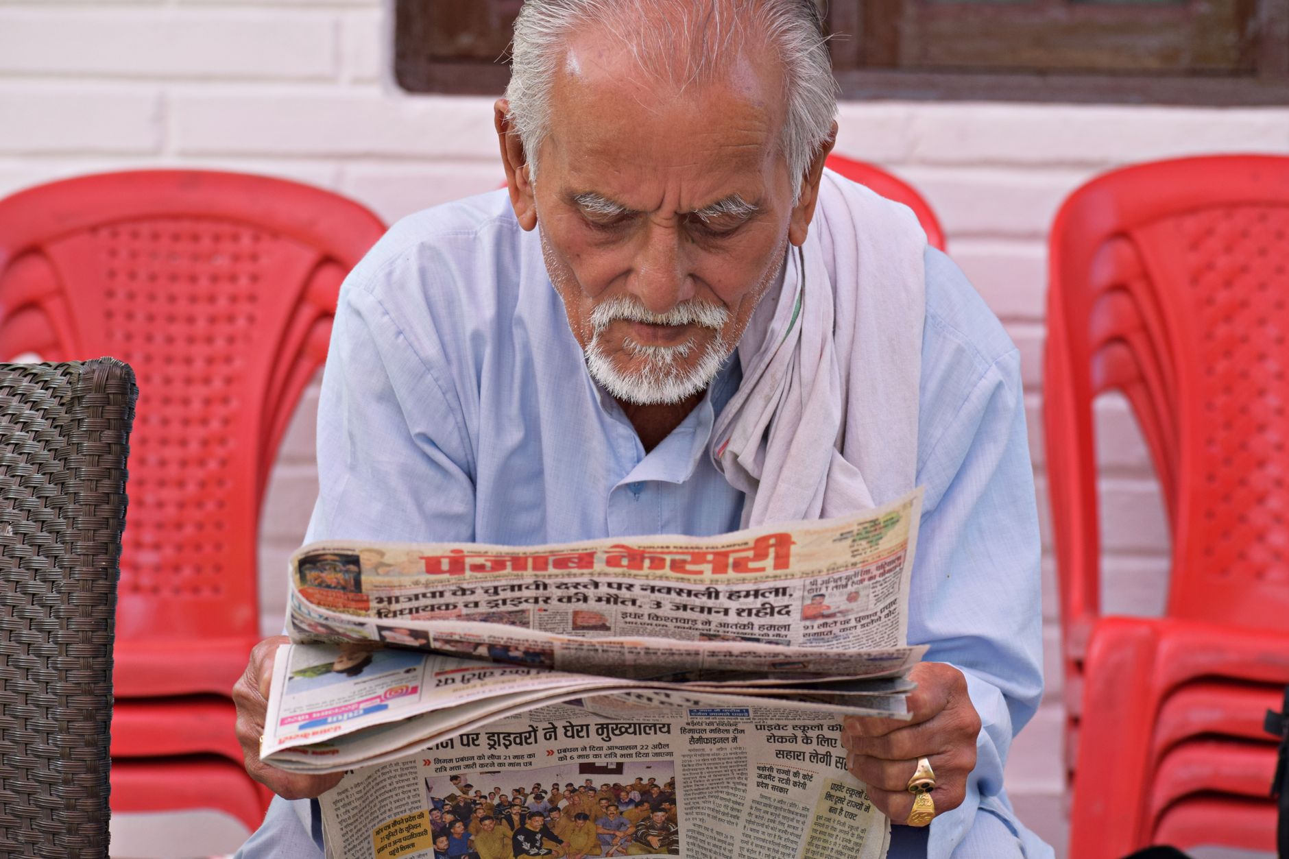 Elderly man engaging in daily reading of a newspaper while seated outdoors. — Pourquoi choisir Casombie Casino pour jouer en
