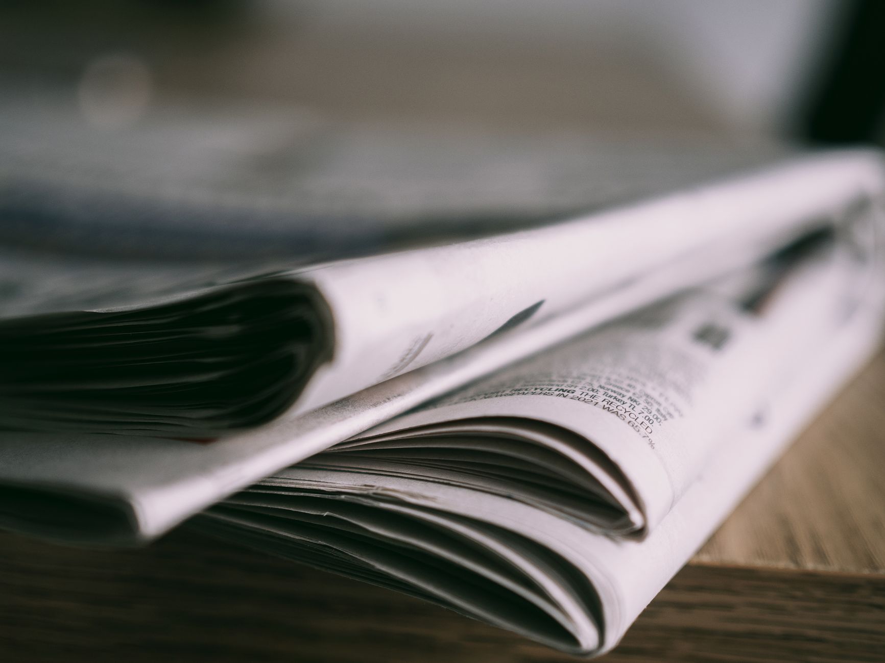 Stack of folded newspapers on a wooden table with a focus on printed pages. — Quels jeux en direct propose Lucky 31 Casino po