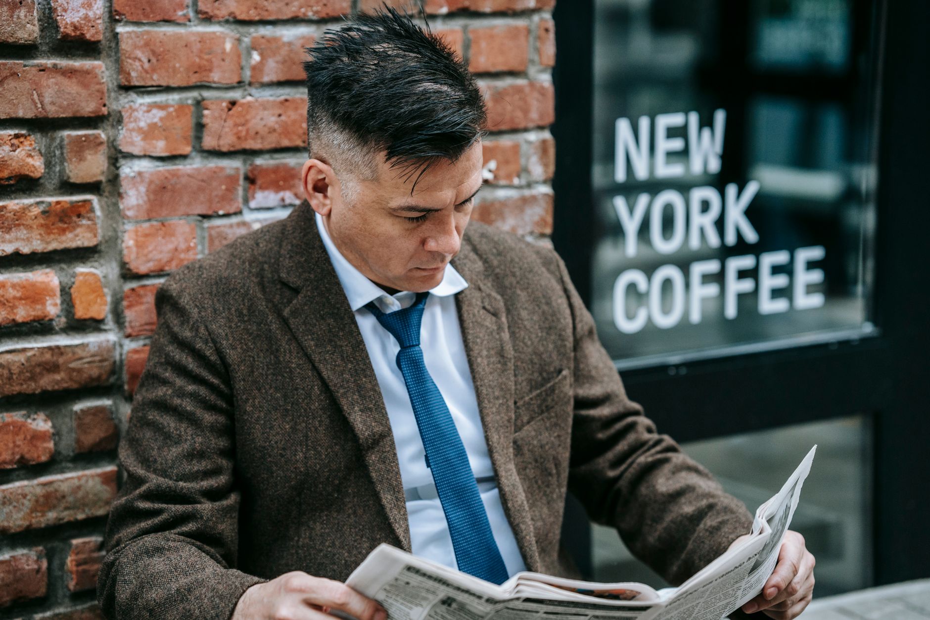 Man in formal attire reading a newspaper outside New York coffee shop. — Quels sont les points forts du profil global de Viny