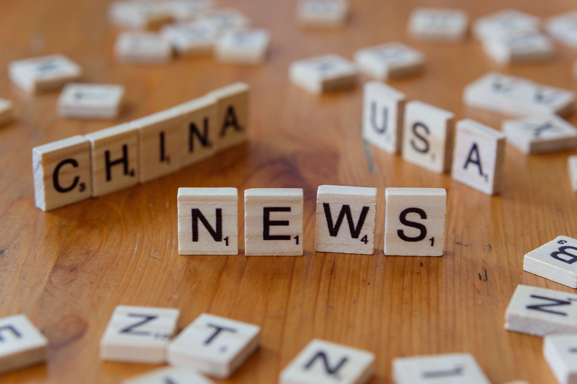 Wooden Scrabble tiles spelling 'NEWS' with 'CHINA' and 'USA' on a wooden surface. — Rabona Casino compatibilité iOS et Androi