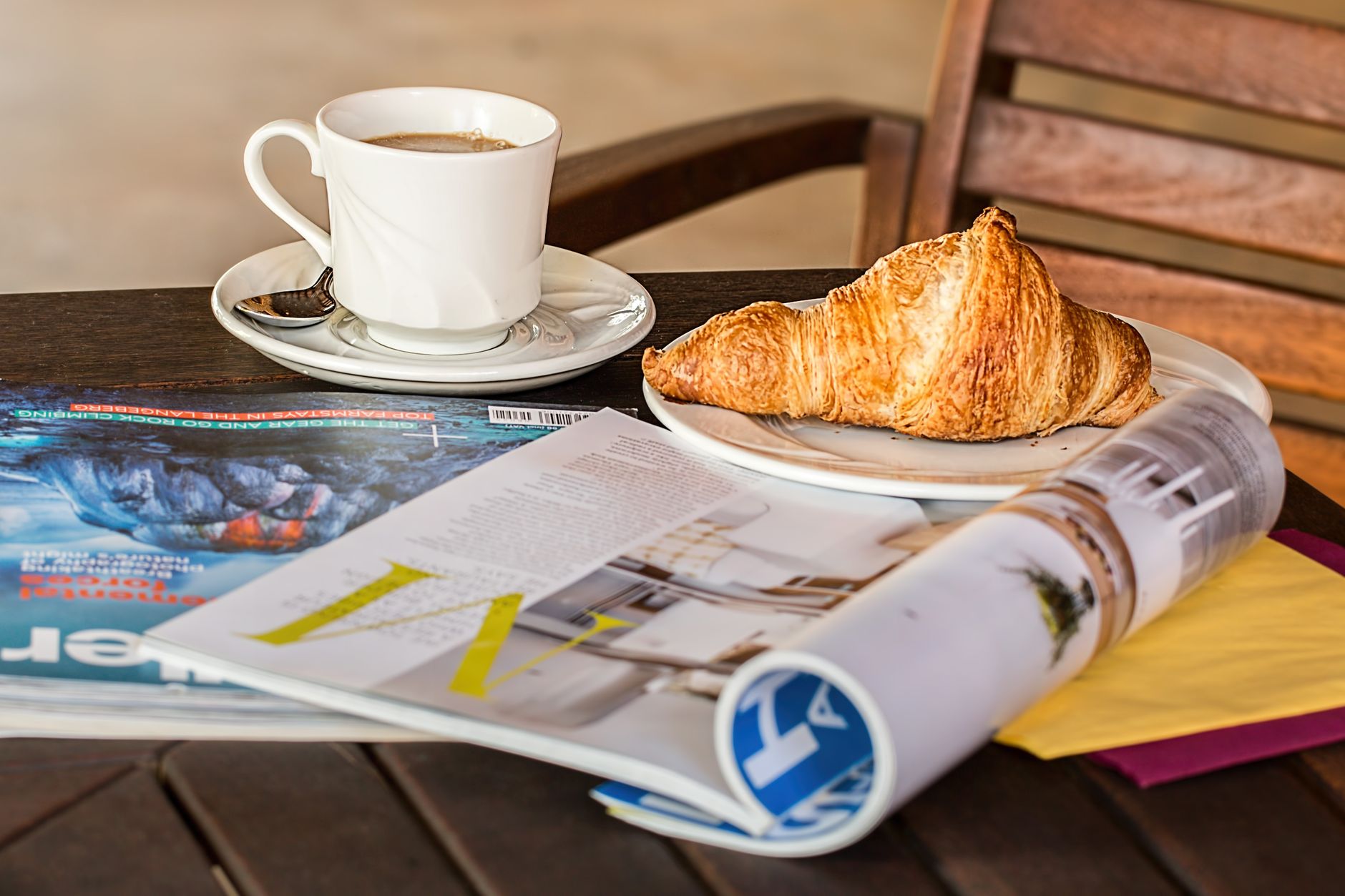 Enjoy a peaceful morning with coffee, croissant, and reading material on a wooden table. — Roby Casino sélection de jeux excl