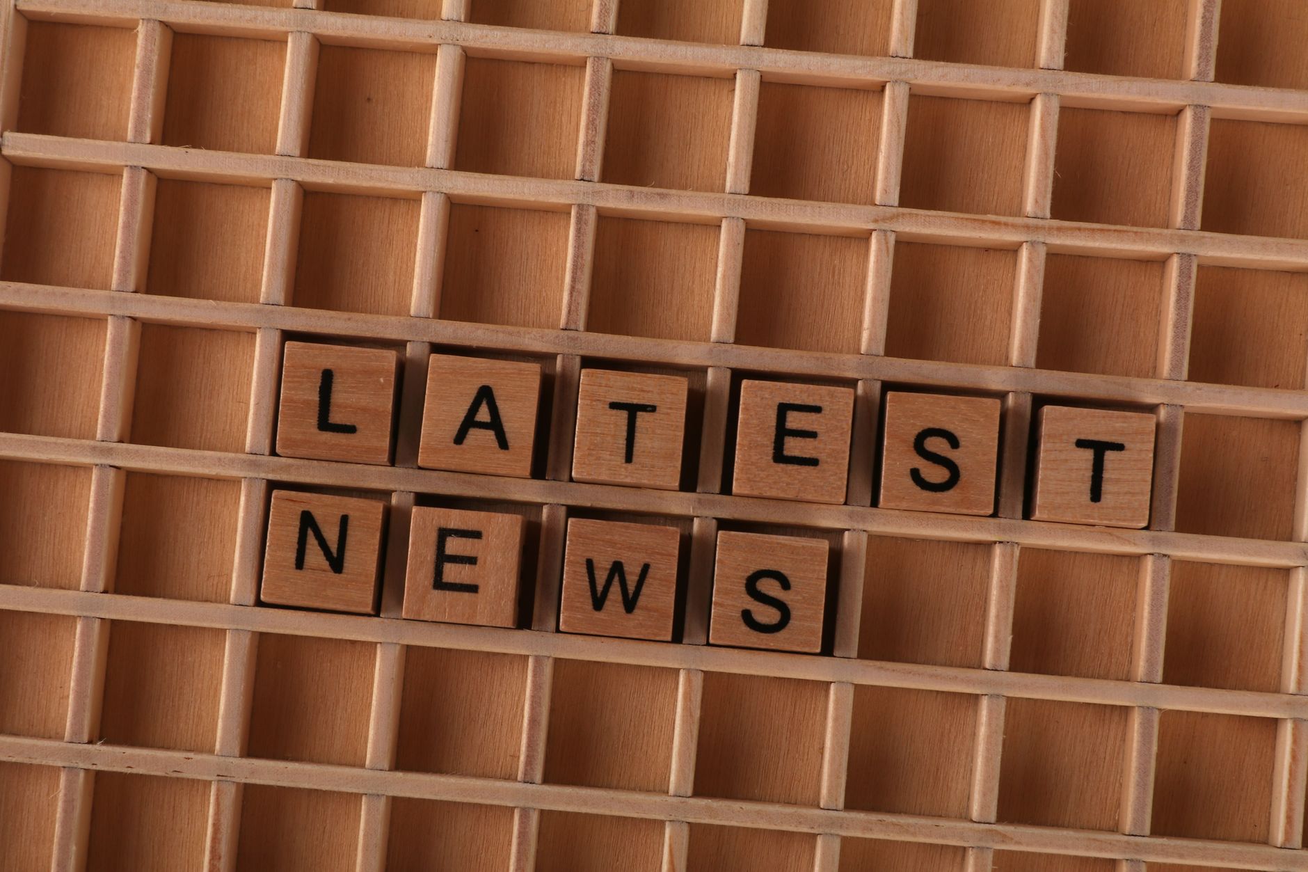 Wooden letter blocks spelling Latest News on a grid background, ideal for media themes. — Royal Ace Casino l’expérience intég