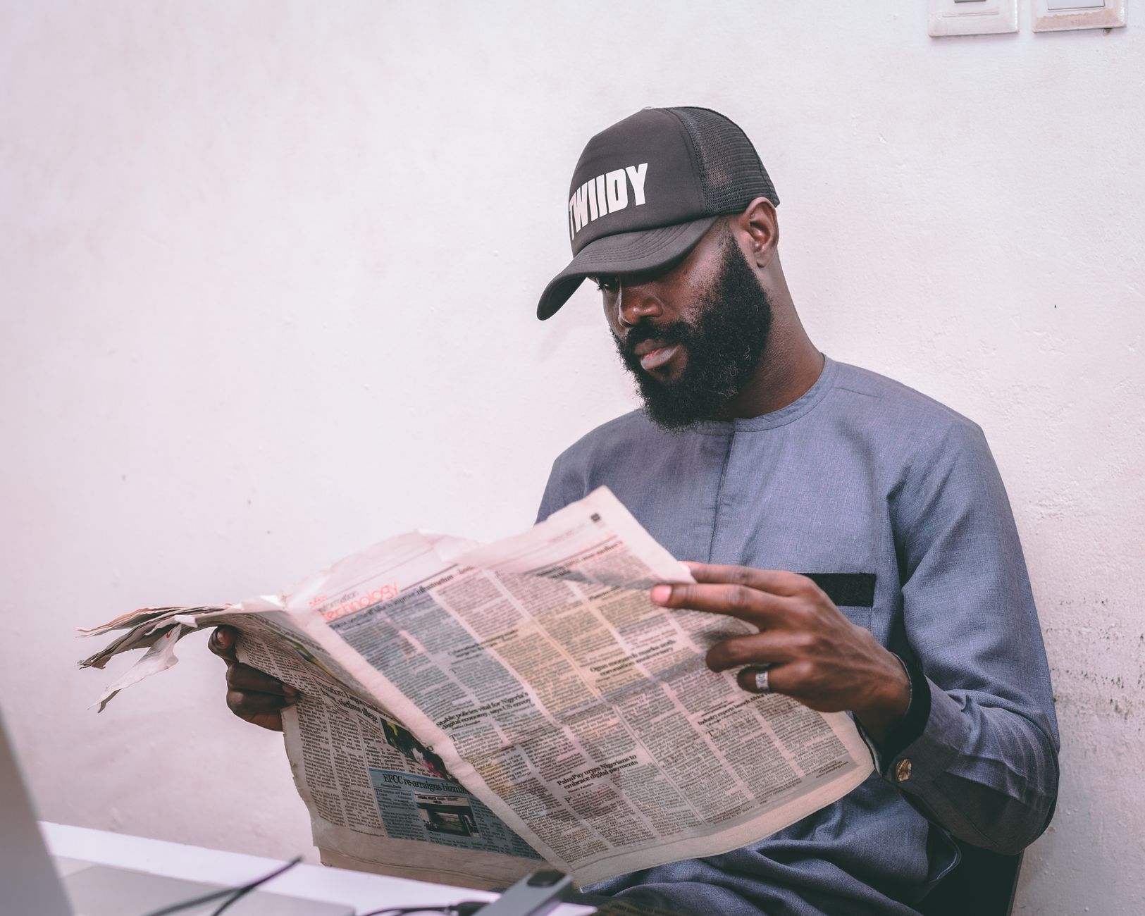 Adult man reading a newspaper indoors, wearing a cap and traditional attire. — Turbo Winz Casino – Ein umfassender Blick auf