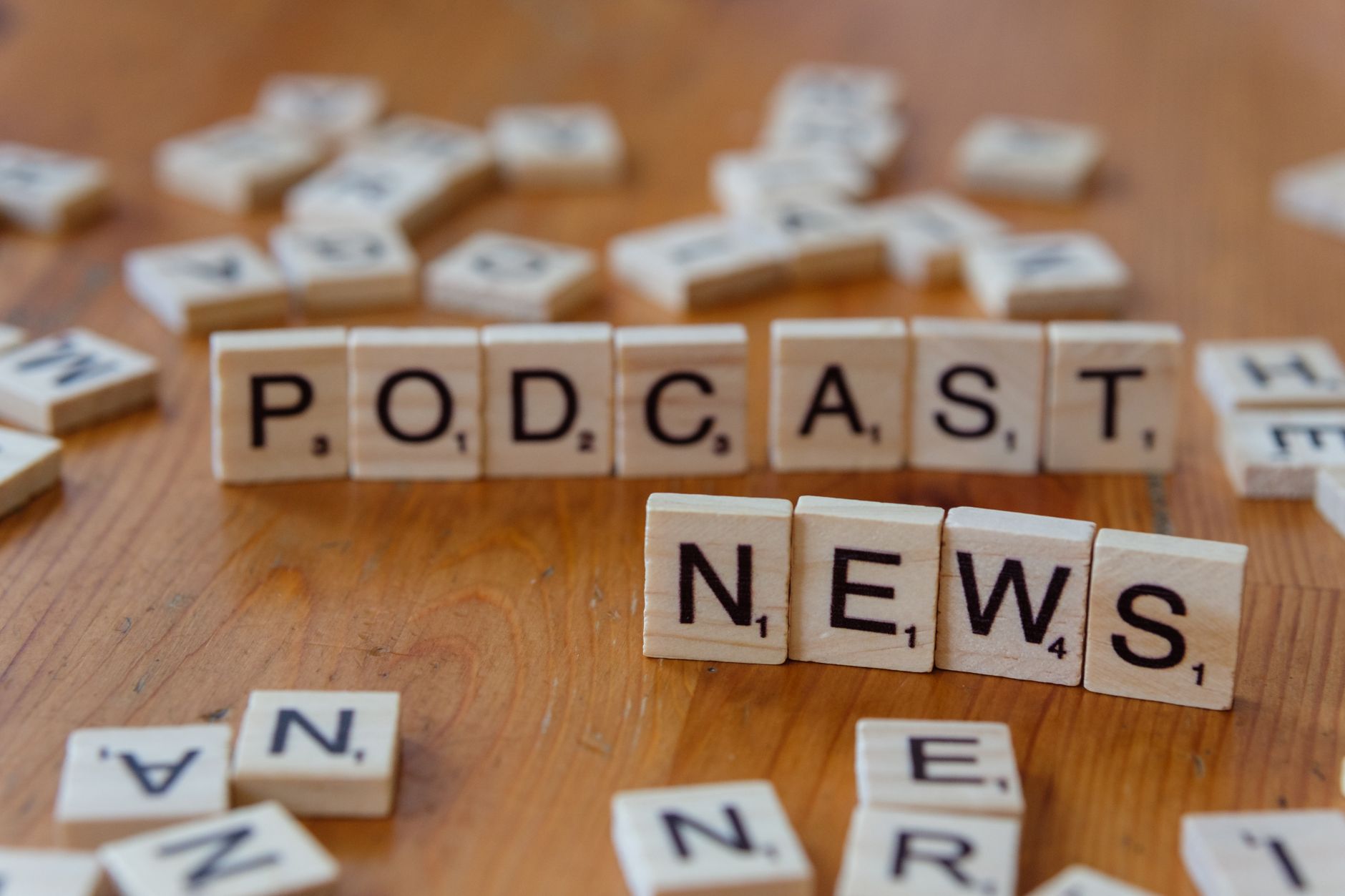Wooden letter tiles spelling out 'PODCAST NEWS' on a wooden surface. — Vegas Plus Casino dernières mises à jour et nouveautés
