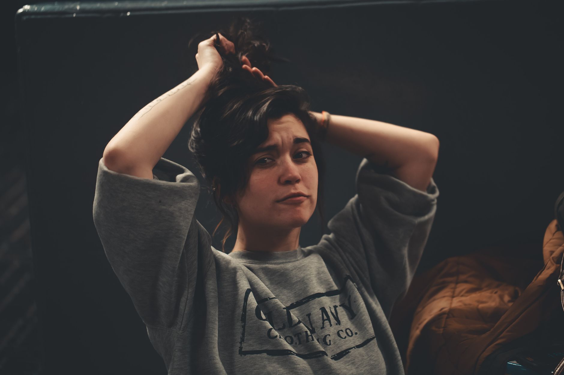A candid portrait of a woman adjusting her hair indoors, showcasing natural beauty and casual style. — What exactly are Pancr