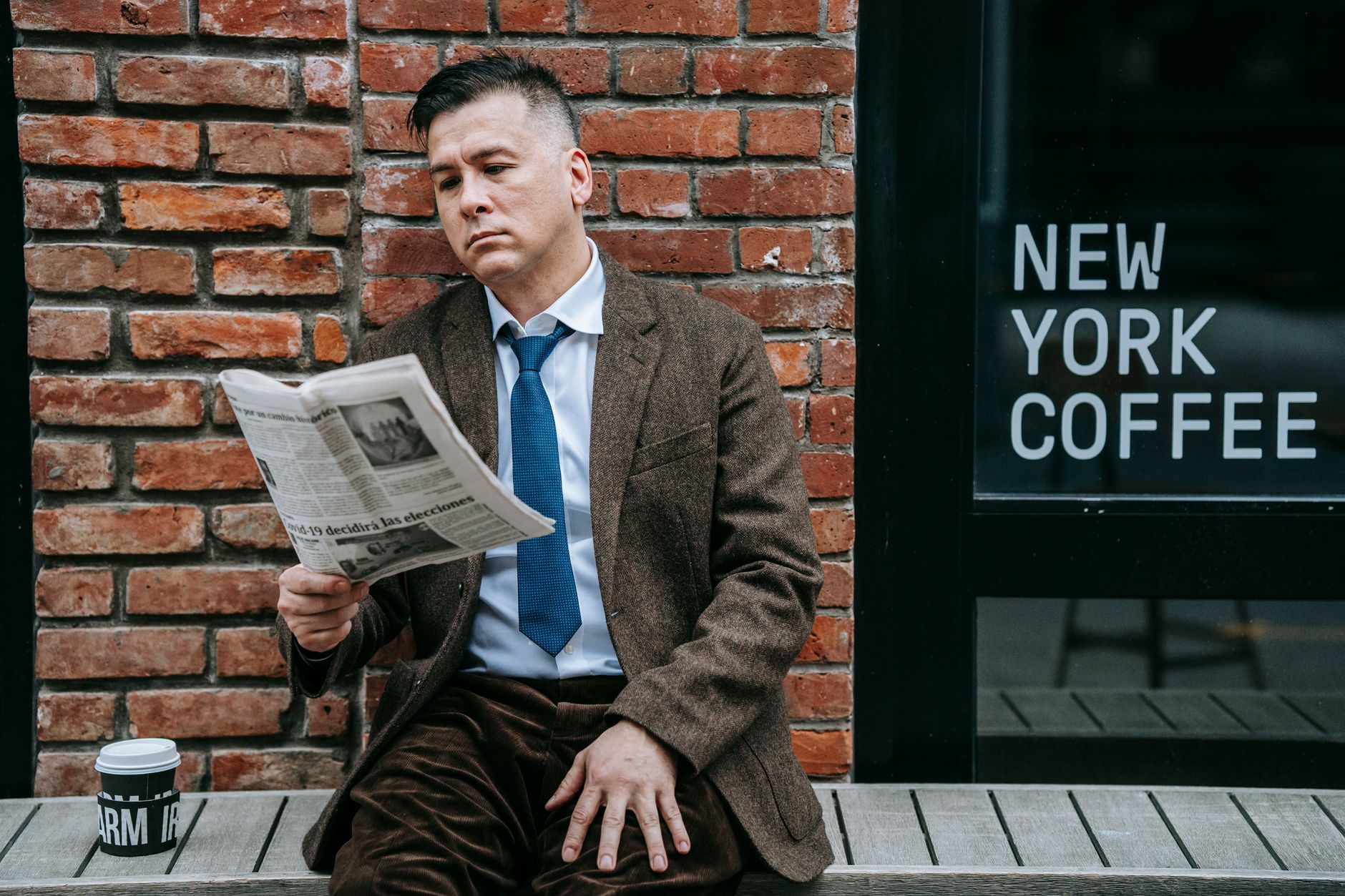 A professional man in formal wear reads a newspaper beside a coffee shop window. — Xon Bet Casino und die Welt der Slots