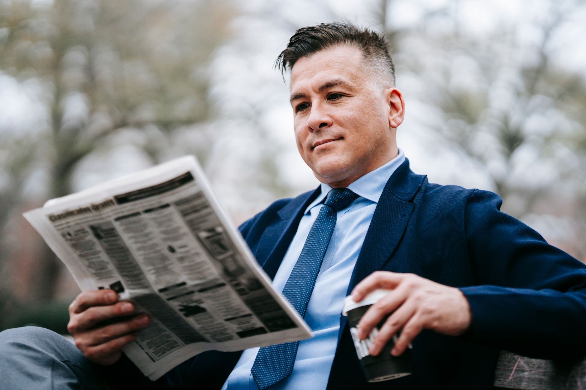 Stylish man in formal wear enjoys a drink while reading a newspaper outside. — Zukünftige Entwicklungen bei Bet22 Casino im B